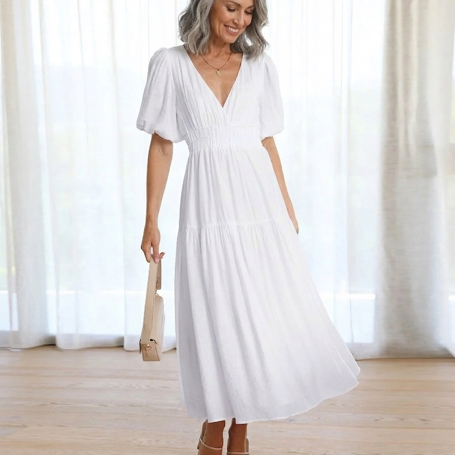 Woman wearing a white dress standing in a room with white curtains.
